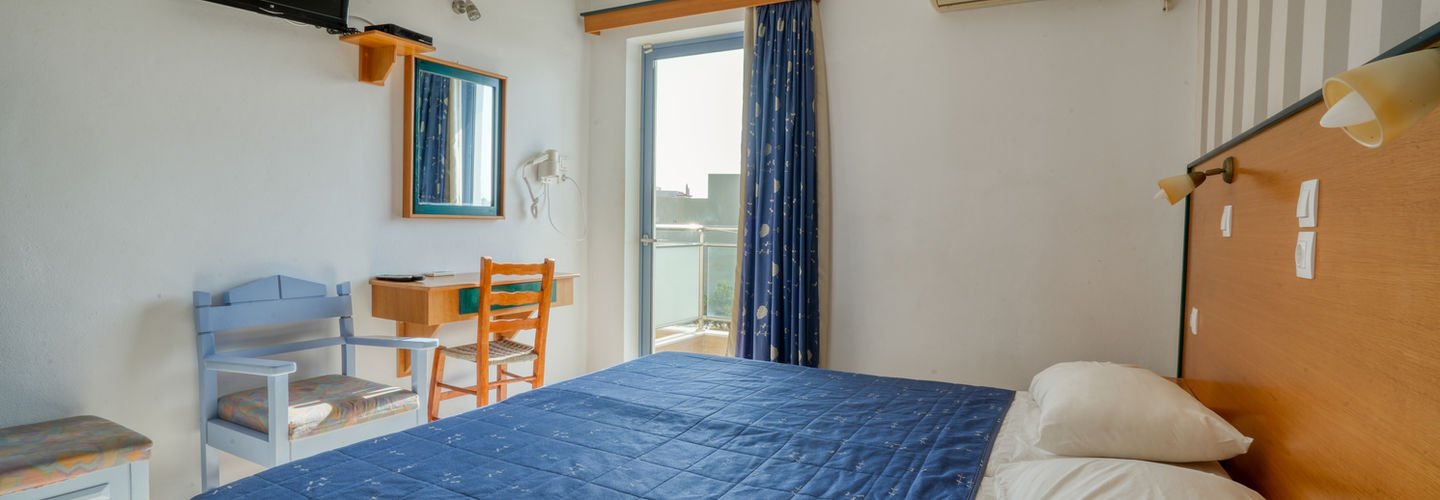 Studio interior with a double bed, seating area and balcony door