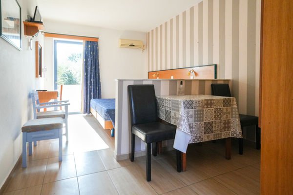 Twin-bedded studio with dining table, kitchenette corner and balcony door