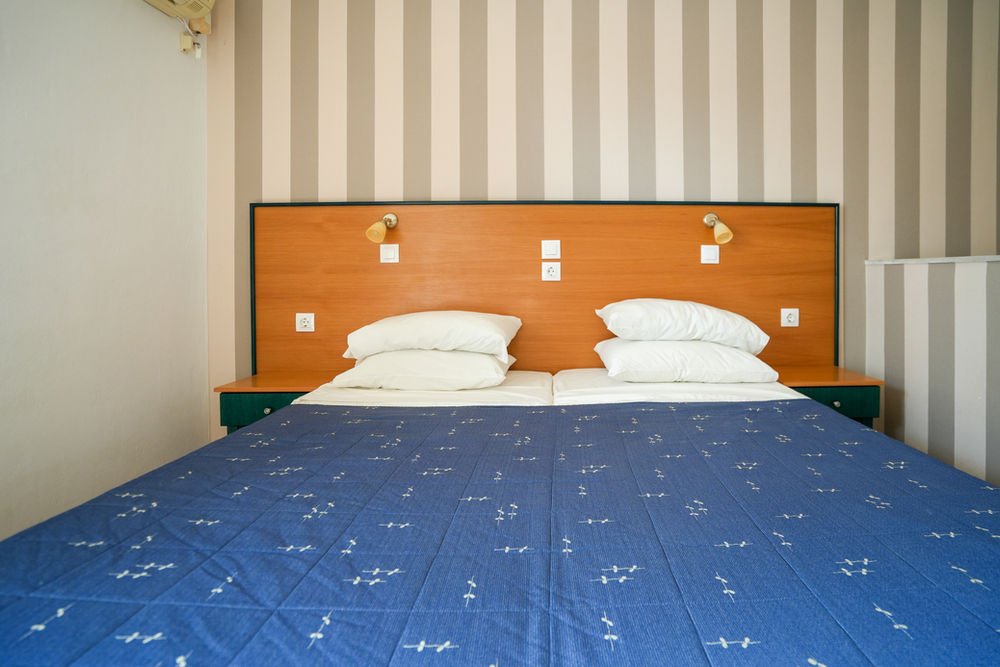 Double bed with a wooden headboard and reading lights in a Paraschos studio
