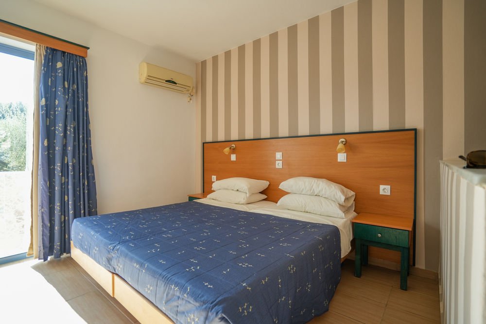 Double bed beside a large balcony window in a first-floor studio
