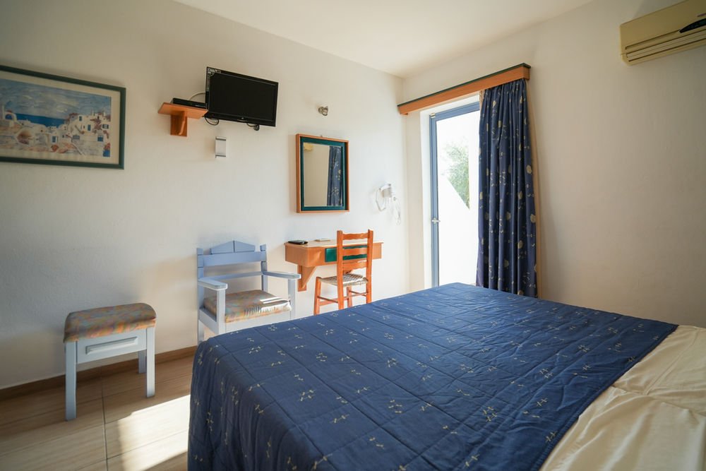 Studio with a double bed, television, dining table and balcony door
