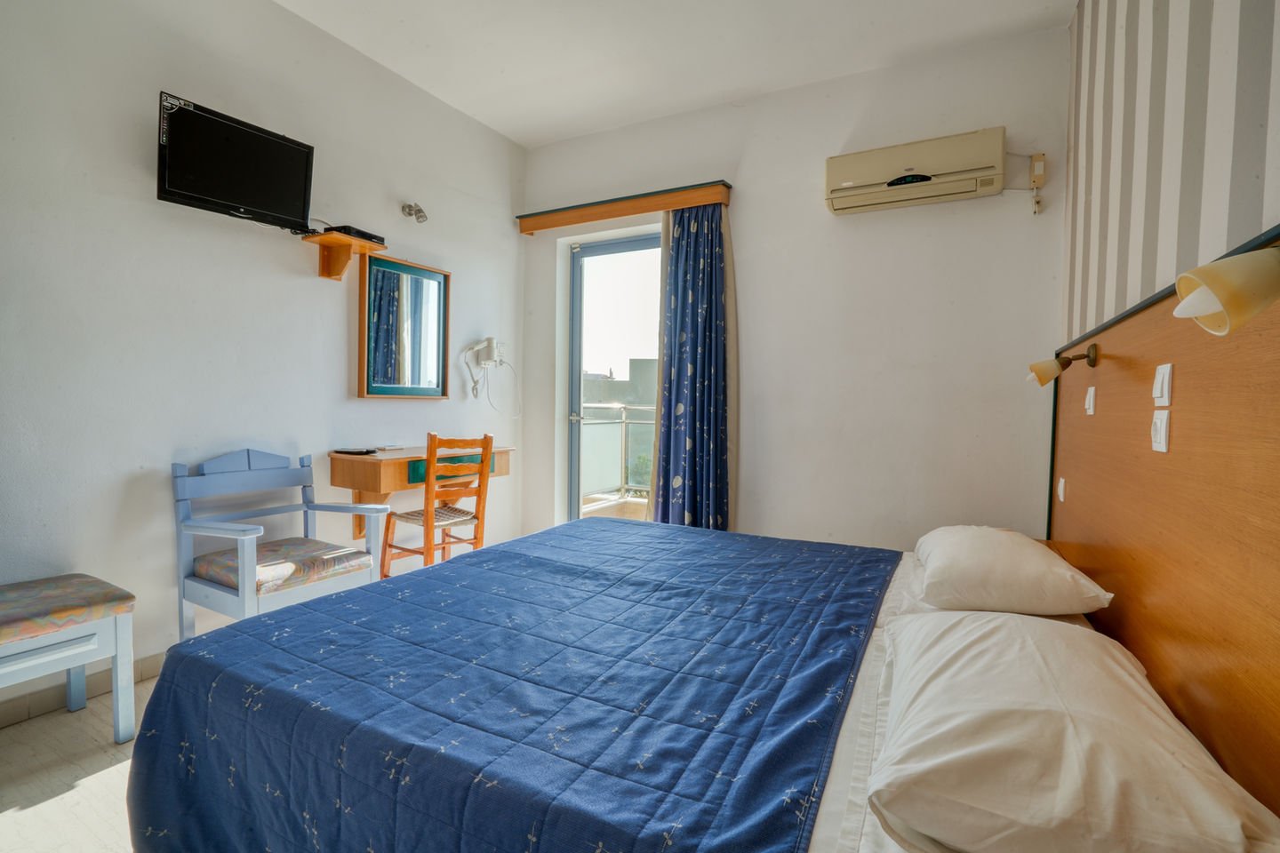 Studio interior with a double bed, television, seating area and balcony door